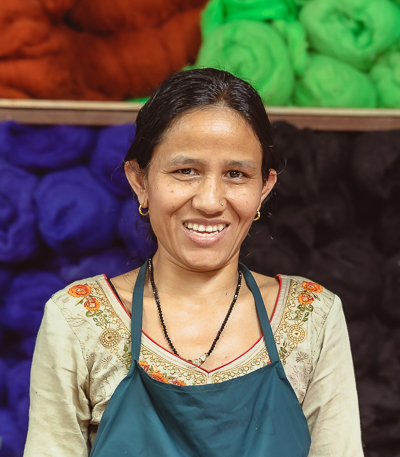 An image of a small felting artisan carefully shaping a small piece of wool with their hands, creating a soft and delicate texture.